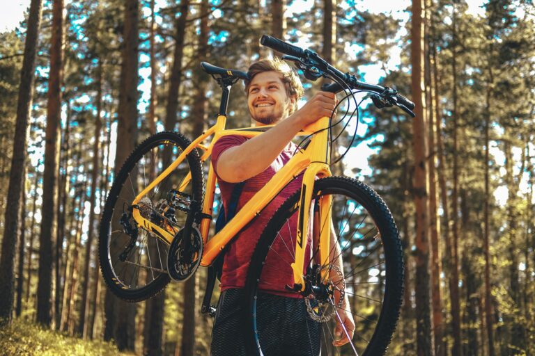 Positive sporty male holding yellow mountain bicycle.